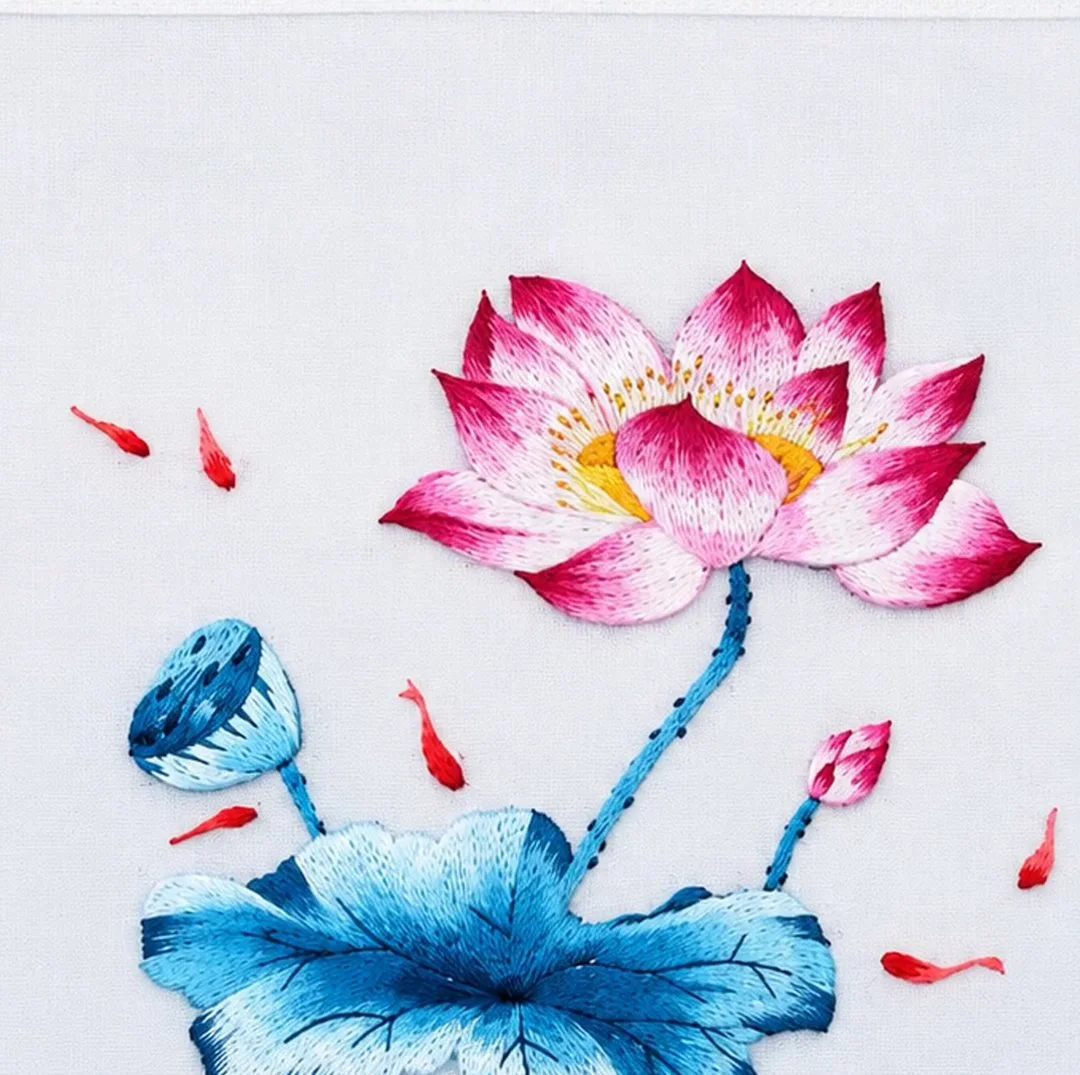 A hand-embroidered pink lotus with blue leaves and small red fish