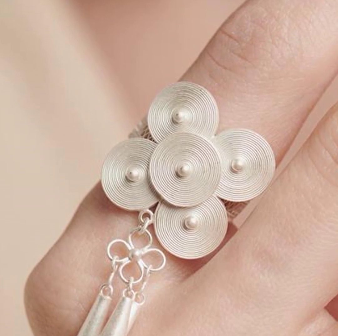 A silver ring of four domed discs with a knotted tassel, worn