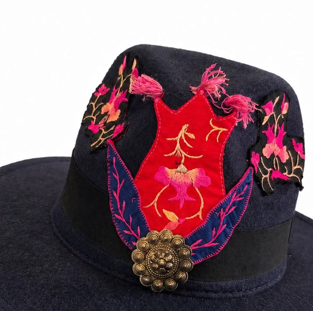 A black felt hat with a red Miao embroidered panel and a bronze button