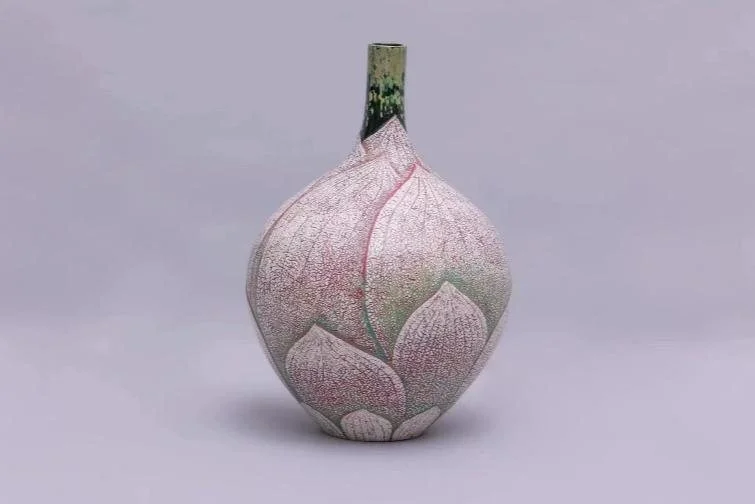 A pale pink vase shaped like a lotus bud on a lilac background