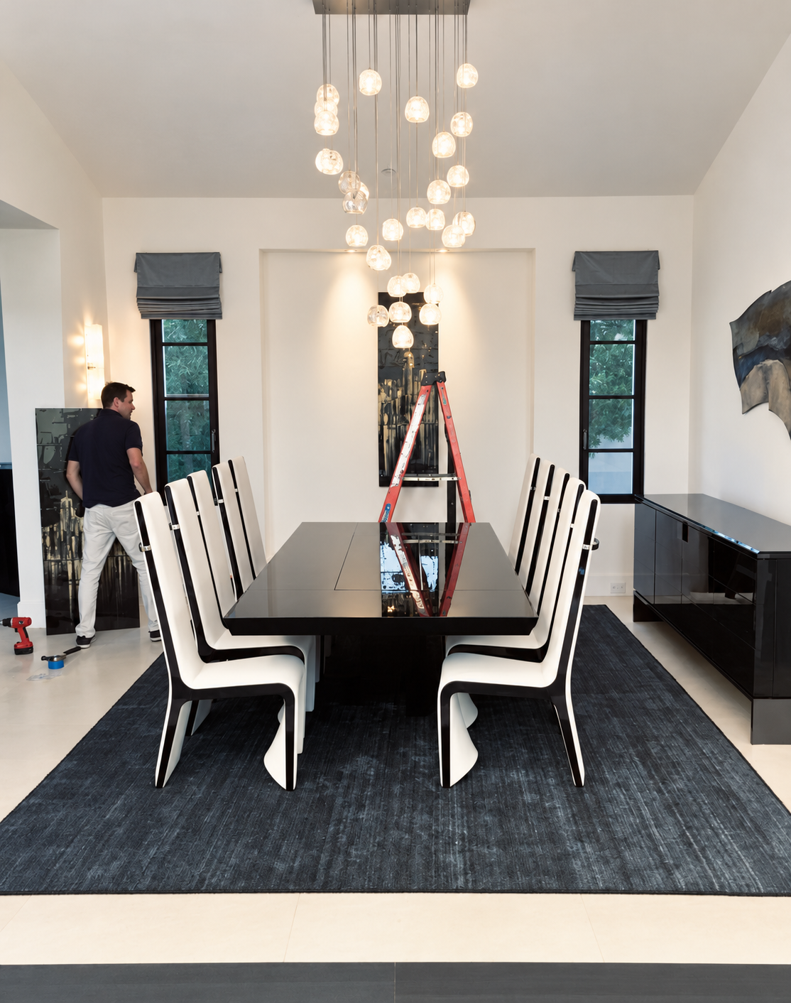 Retouched photograph of artwork installation in a dining room, with the installer and ladder