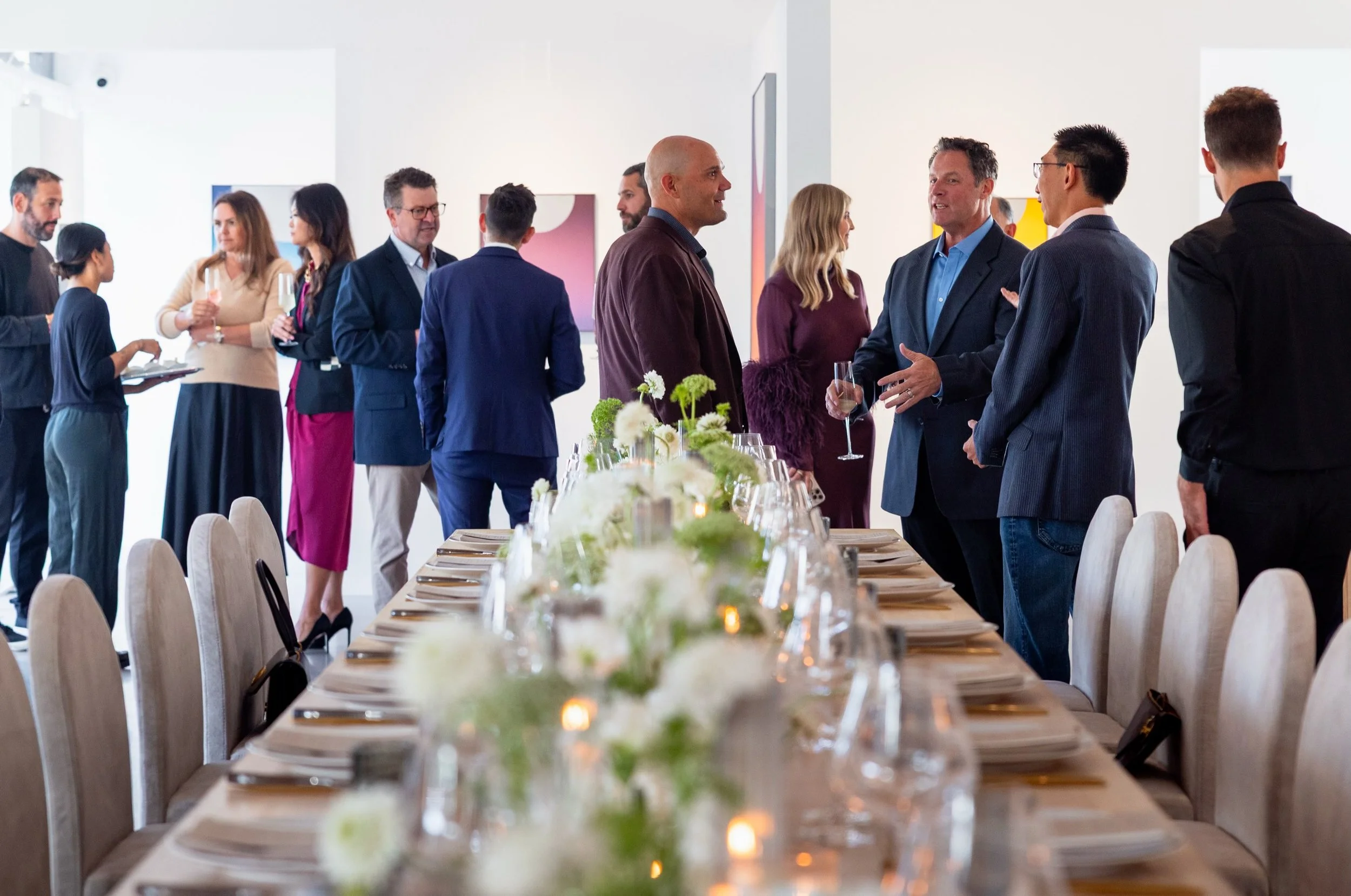 Guests mingling beside a collector dinner table at an event by Laguna Beach Art Agency