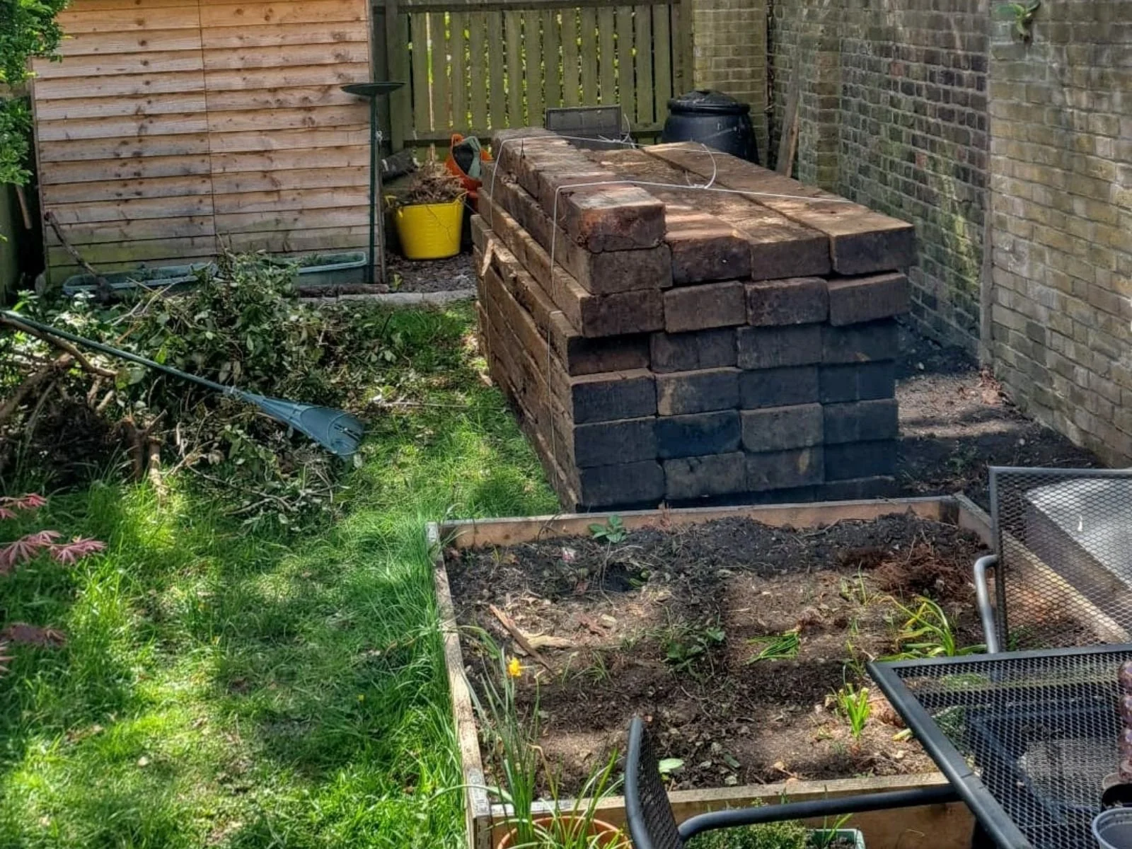 Small London garden before landscaping with stacked materials and disorganised layout