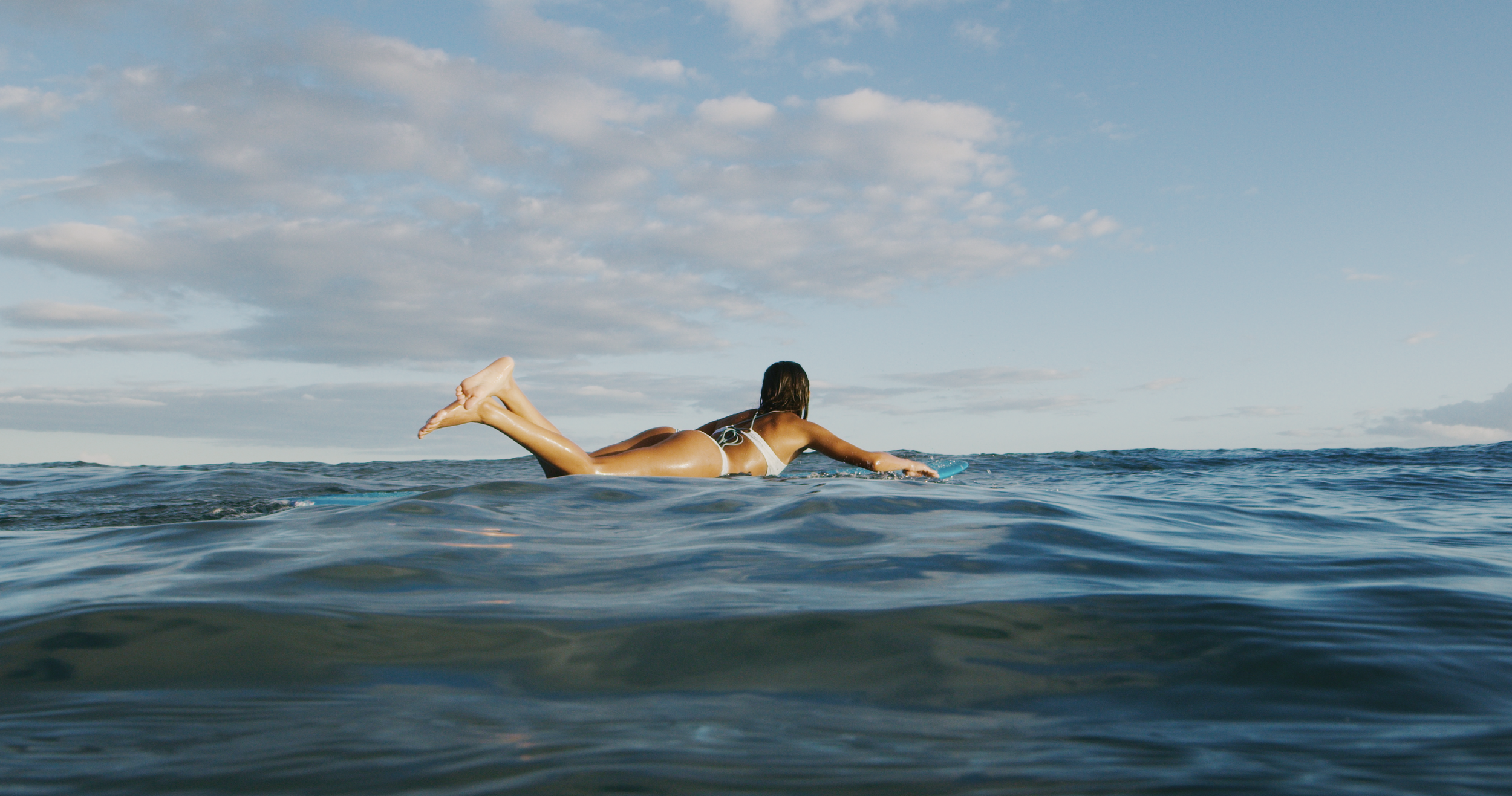 Girl lying down on a surfboard during a Makai Surf Club lesson