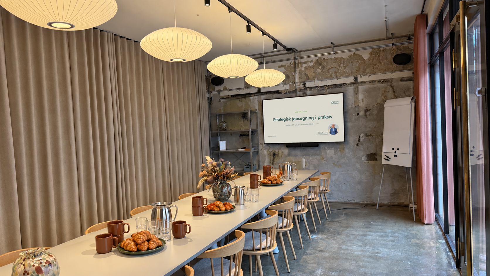 Kursuslokalet hos Nordstens Workspace i Hillerød med langbord, kaffe, croissanter og præsentationen Strategisk jobsøgning i praksis på skærmen