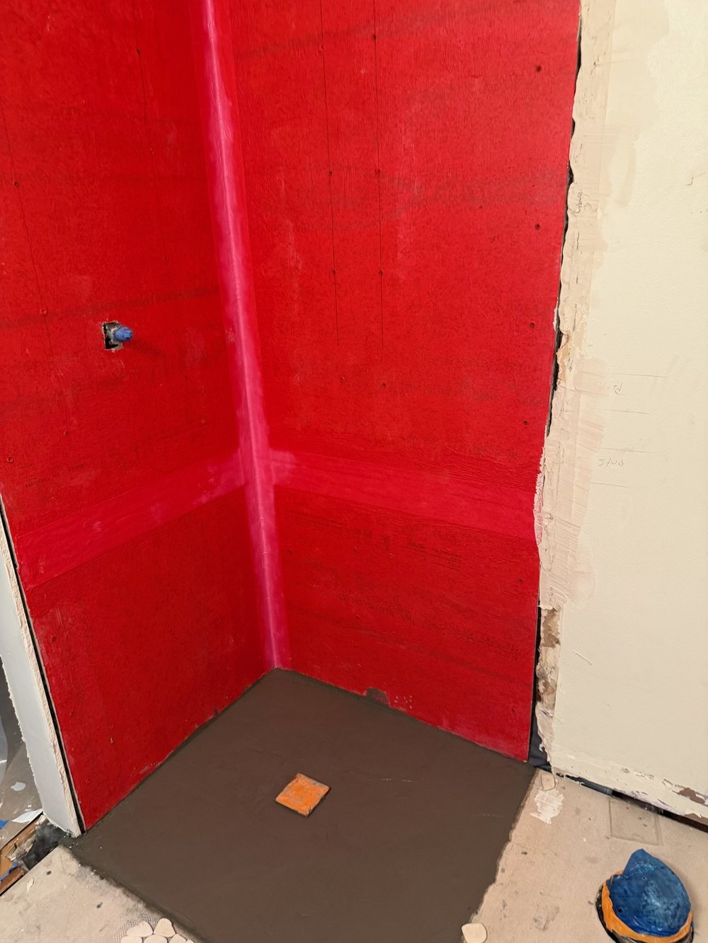 Red waterproofing membrane applied to shower walls during construction