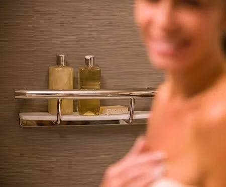 Load-rated grab bar with an integrated shampoo shelf mounted in a tiled shower