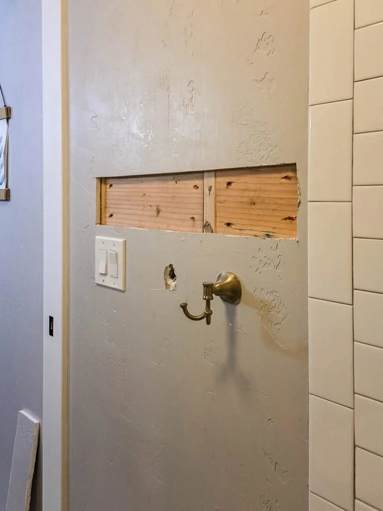 Wall opened during installation showing solid wood blocking set for a grab bar