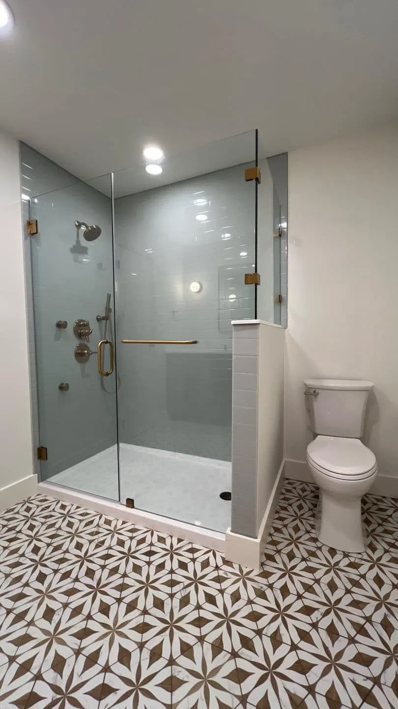 Walk-in shower with brass fixtures and patterned tile