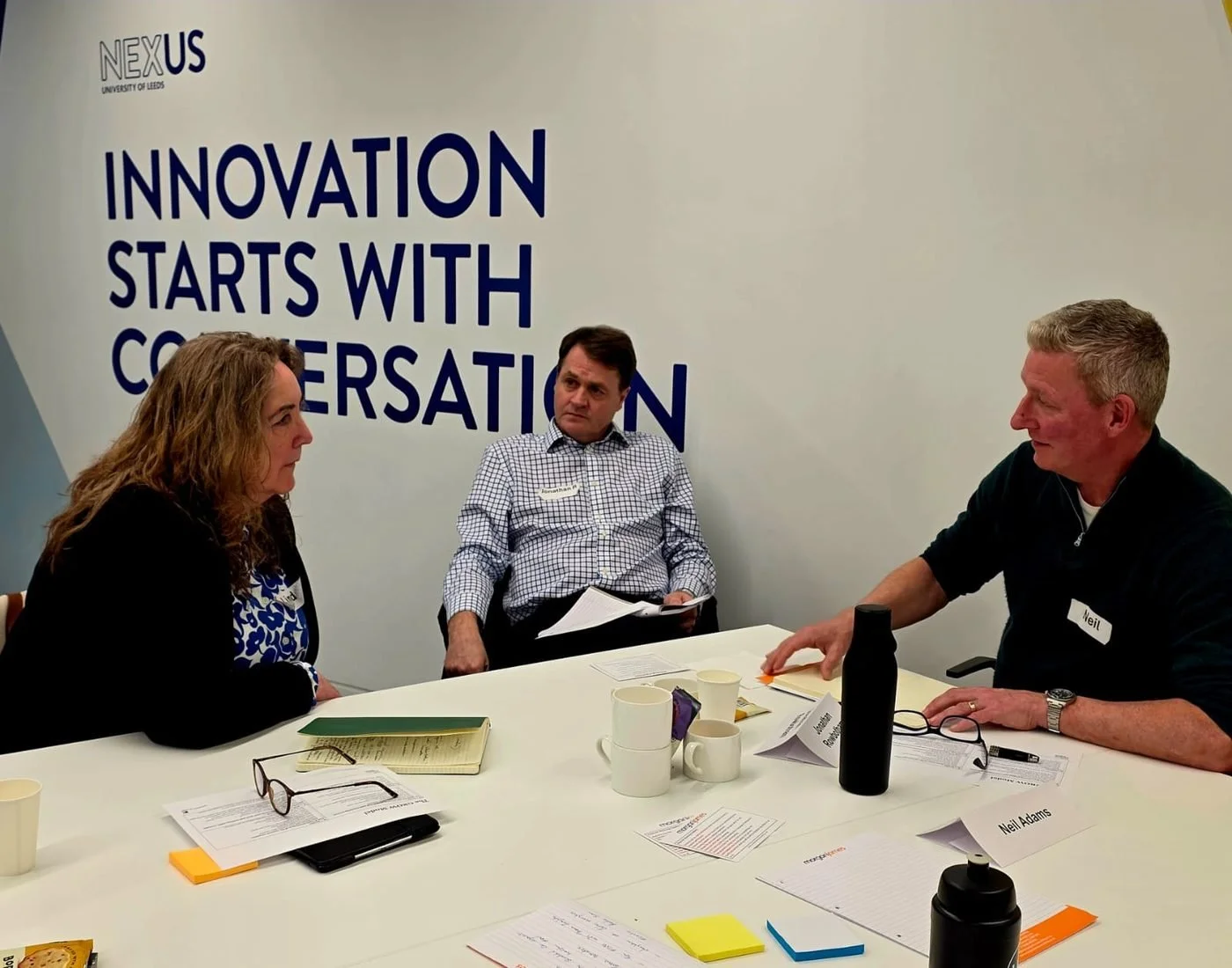 Neil in conversation with two founders around a table