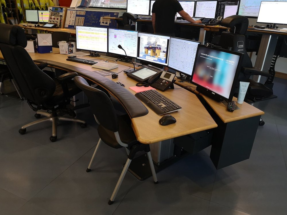 Operativ arbeidsplass med buet bordflate, skjermer og betjeningsutstyr