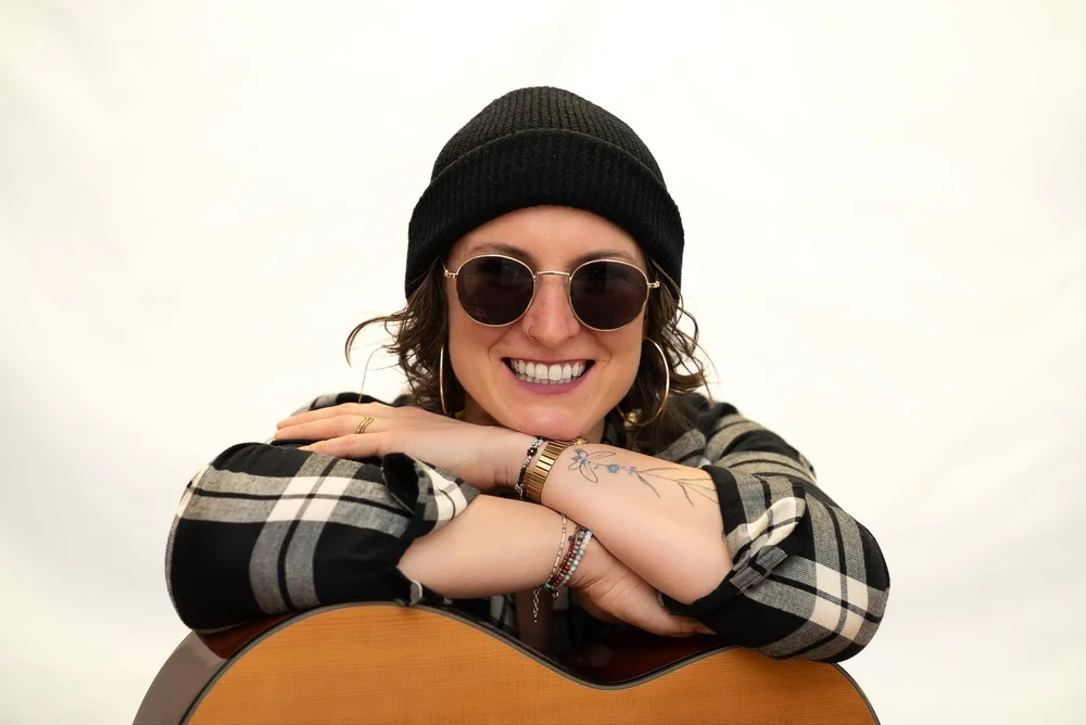 Lachende Musikerin mit Sonnenbrille und Gitarre