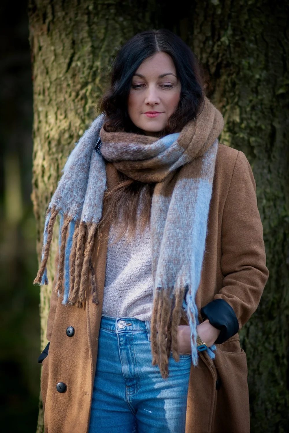 Frau mit Schal an einem Baum