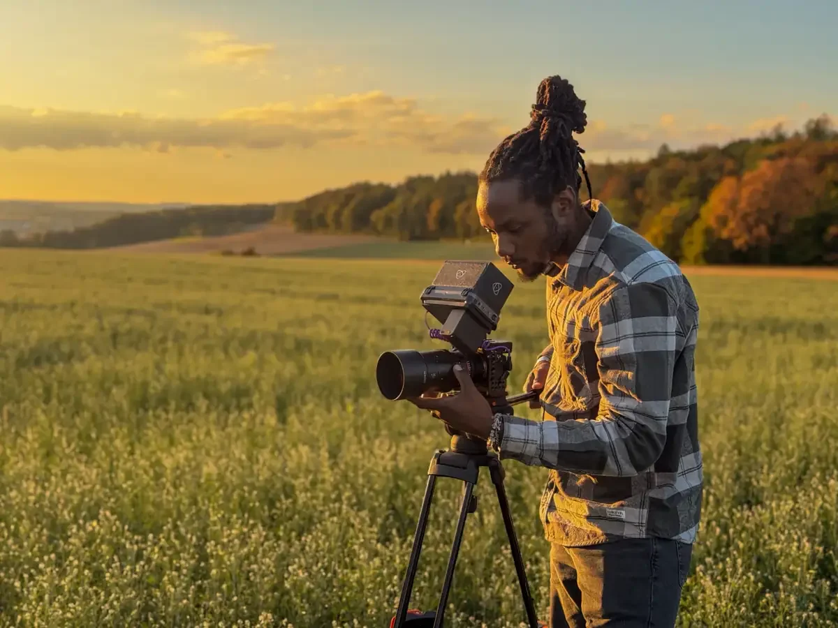 Filmemacher richtet seine Kamera auf dem Stativ bei Sonnenuntergang auf einem Feld bei Ulm ein
