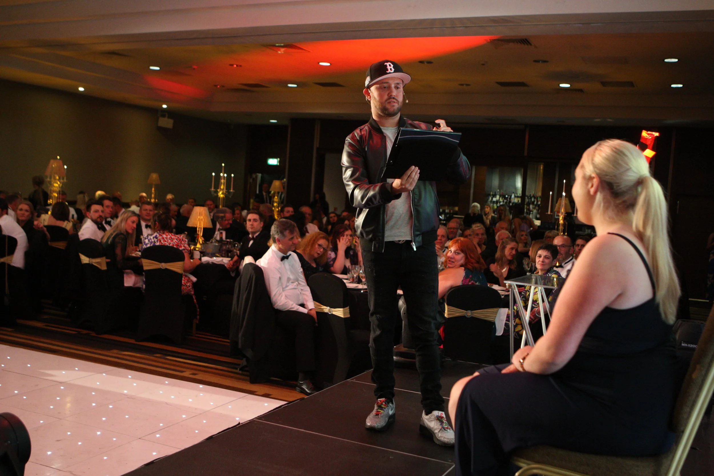Damien O'Brien performing mind reading live on stage in front of a large seated audience