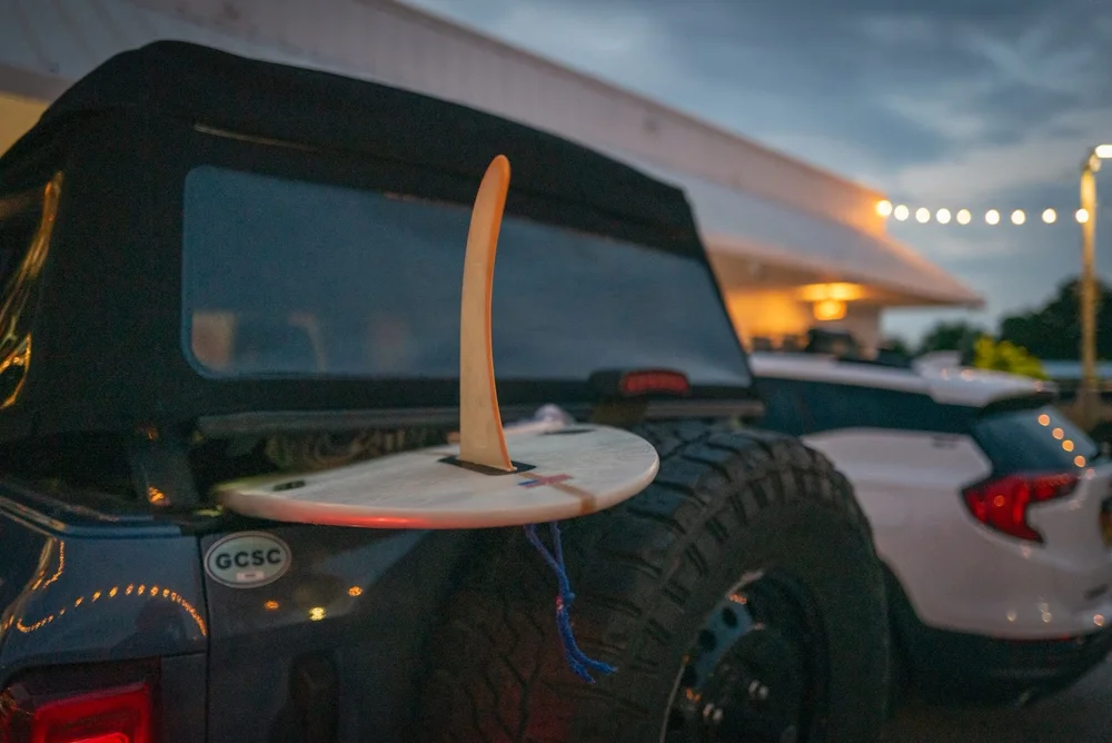 Surfboard fin on a Bronco at dusk under string lights