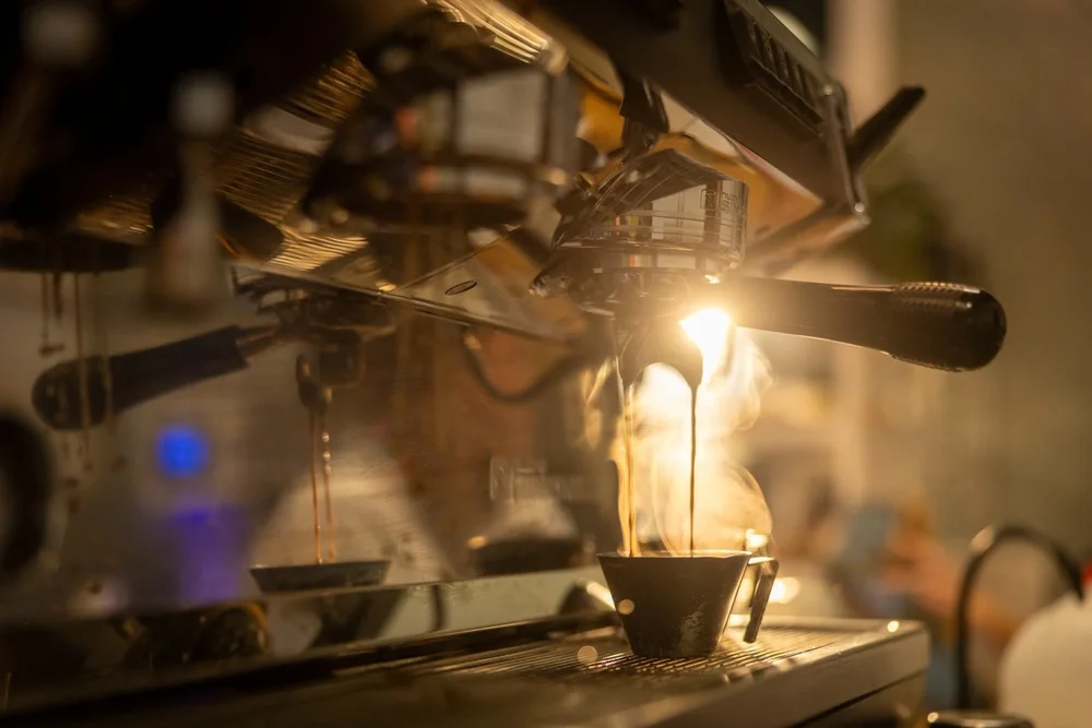 Espresso pulling, backlit with steam