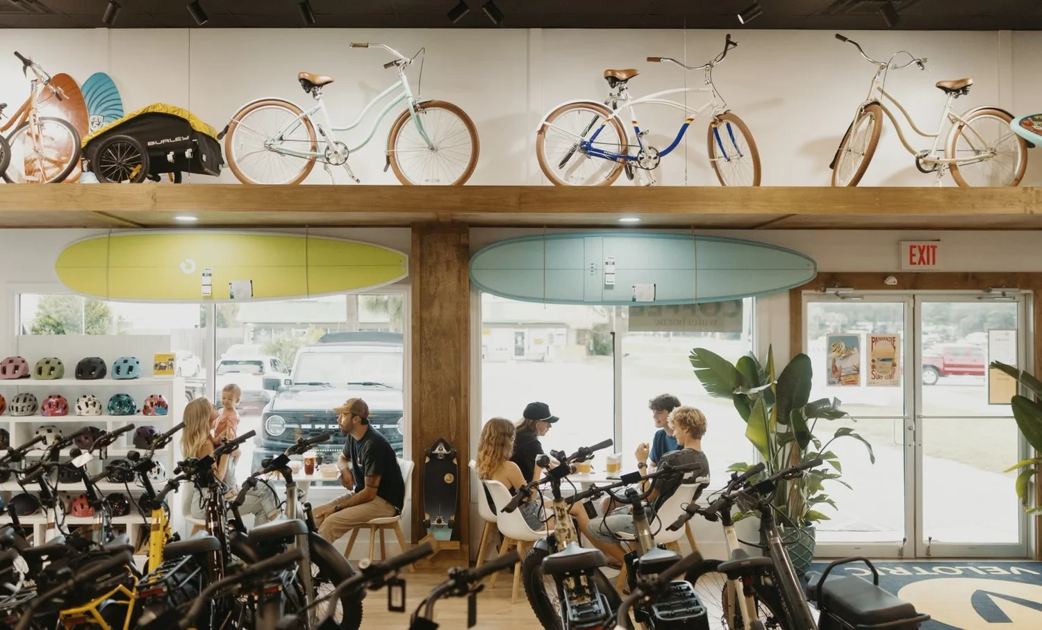 Inside Waterborne: friends at tables under surfboards and cruiser bikes