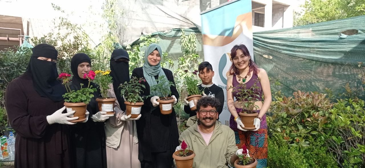 Neighbors hold the potted flowers they planted together