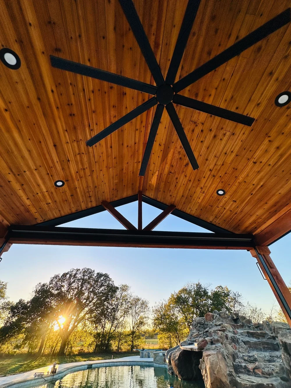 Tongue-and-groove pavilion ceiling with large fan and recessed lighting overlooking the Munday pool