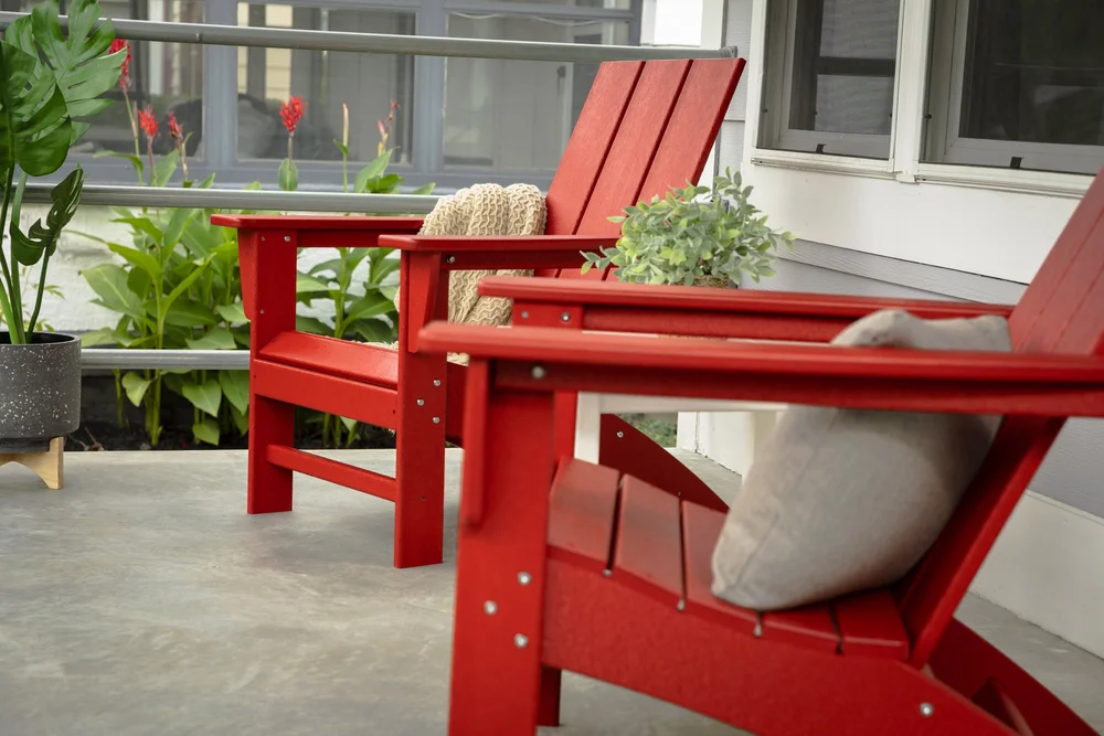 Red POLYWOOD Adirondack chairs arranged on a covered porch