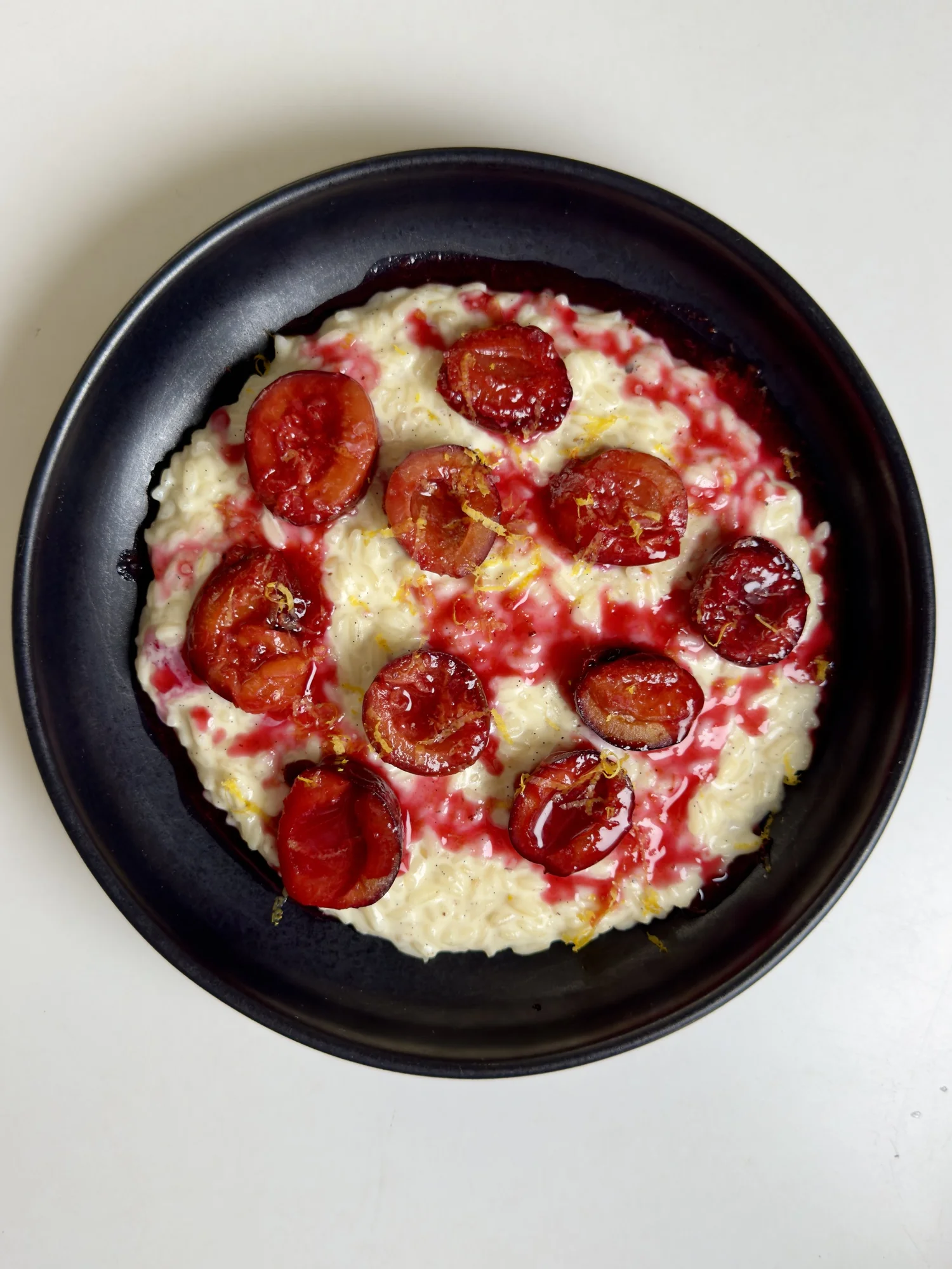 Milchreis with plum compote on a black plate
