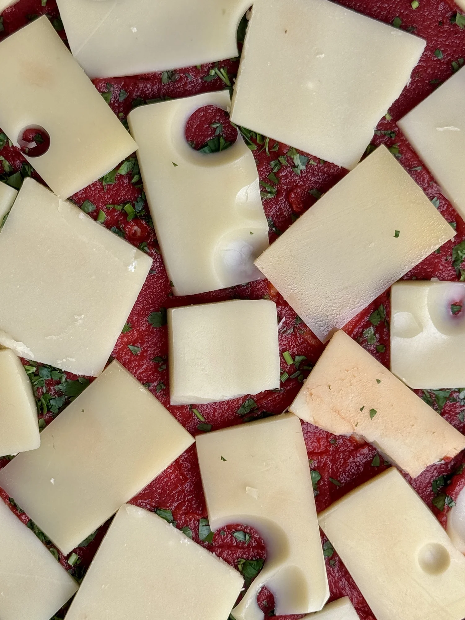 Tomatenkuchen before baking, sliced cheese on tomato paste