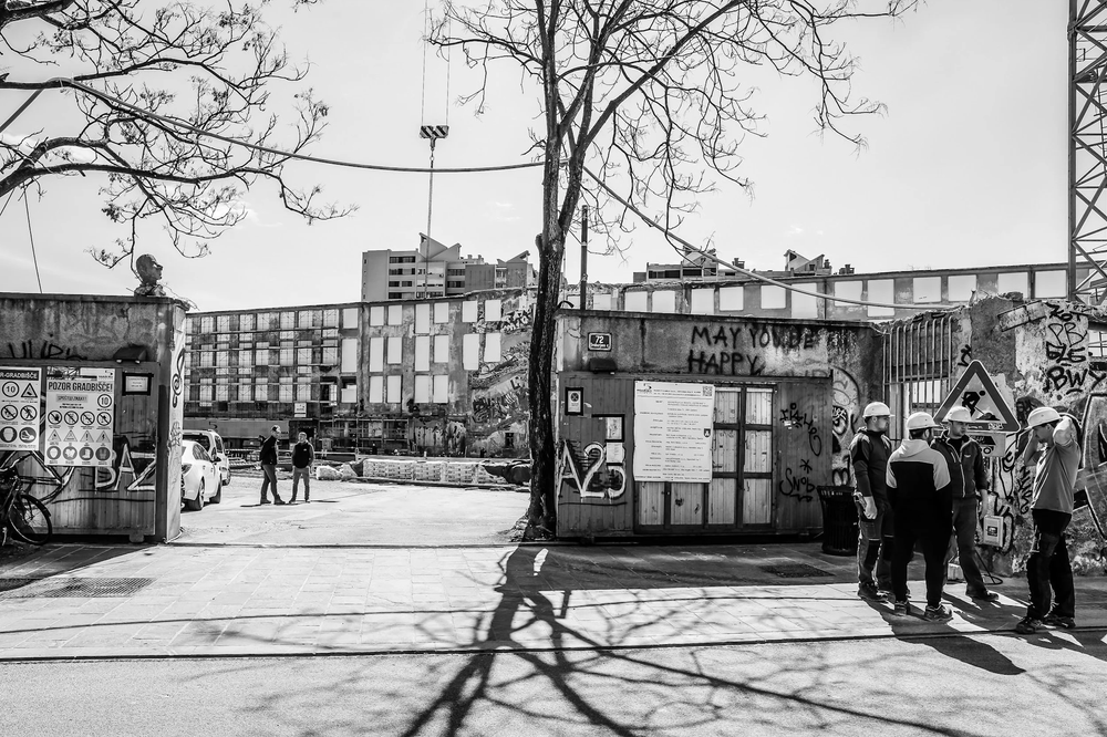 Black-and-white street scene with people beside Ljubljana's riverside market