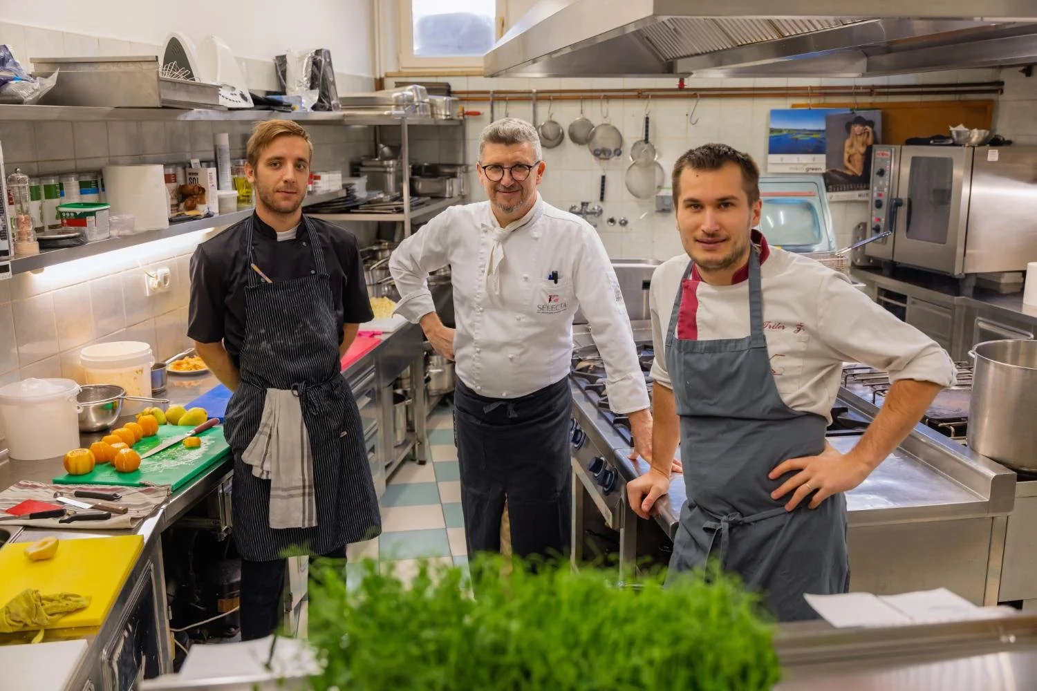Three members of the Gostilna Krištof kitchen team stand between kitchen work surfaces.