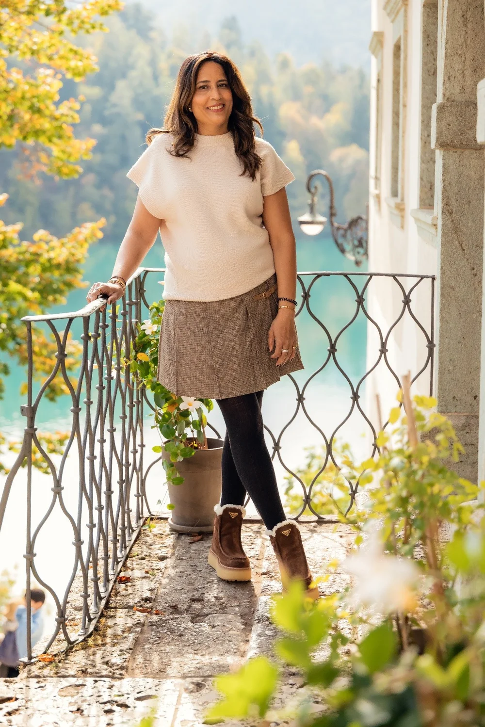 An individual portrait by a railing above Lake Bled, framed by autumn foliage.