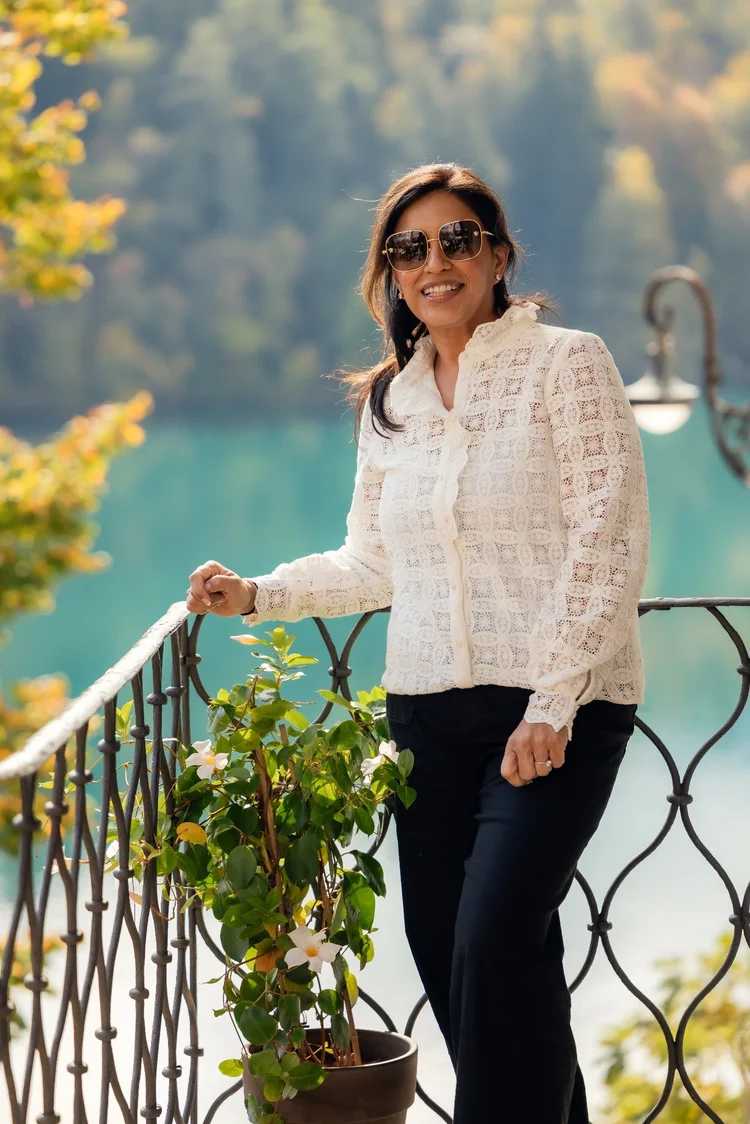 Woman in a white lace blouse and sunglasses by Lake Bled.