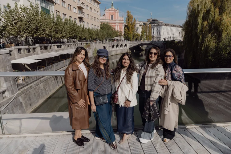 Five friends on a bridge above the Ljubljanica in central Ljubljana, with the Triple Bridge and Franciscan Church behind them.