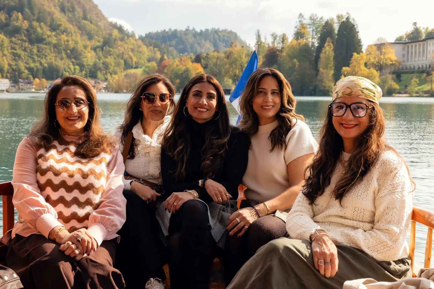 Five friends sitting together in a wooden boat on Lake Bled.