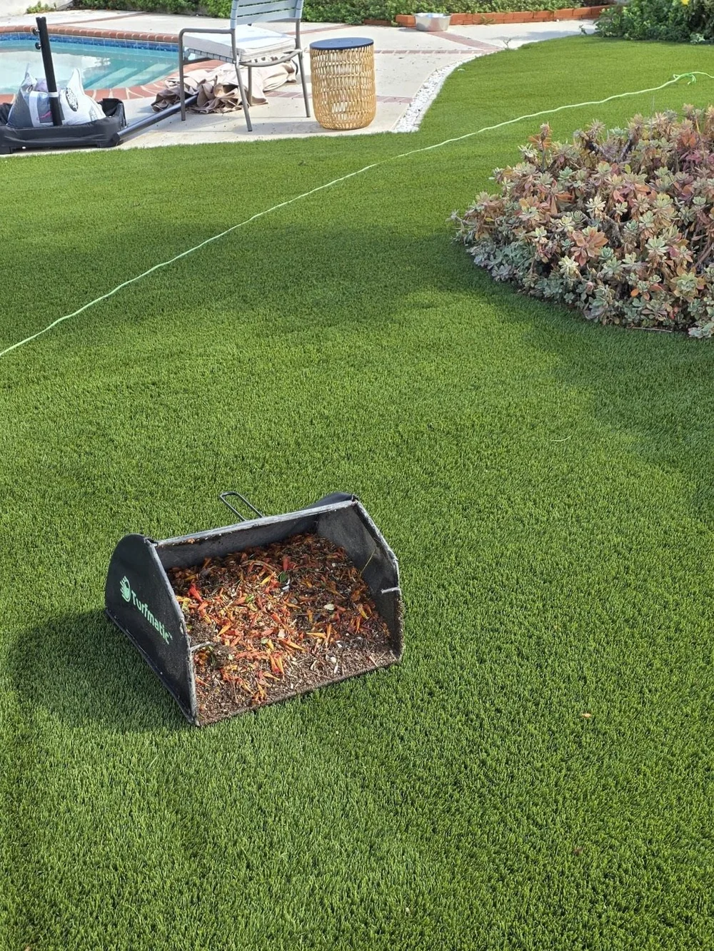 Hydroforce sweeper bin full of flower petals and debris pulled from artificial turf