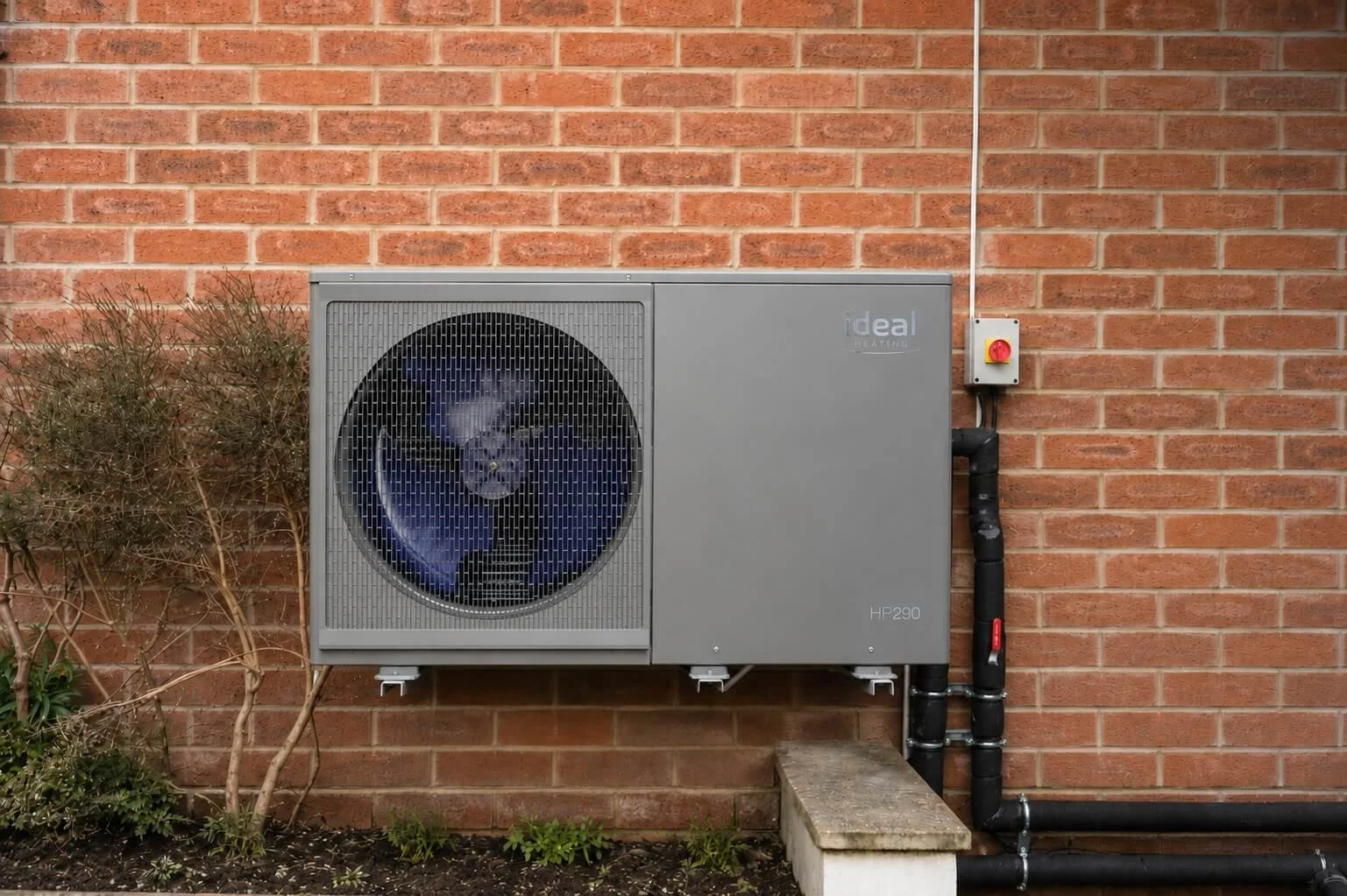 Ideal Heating Logic HP290 air source heat pump installed against the brick wall of a house in Tavistock