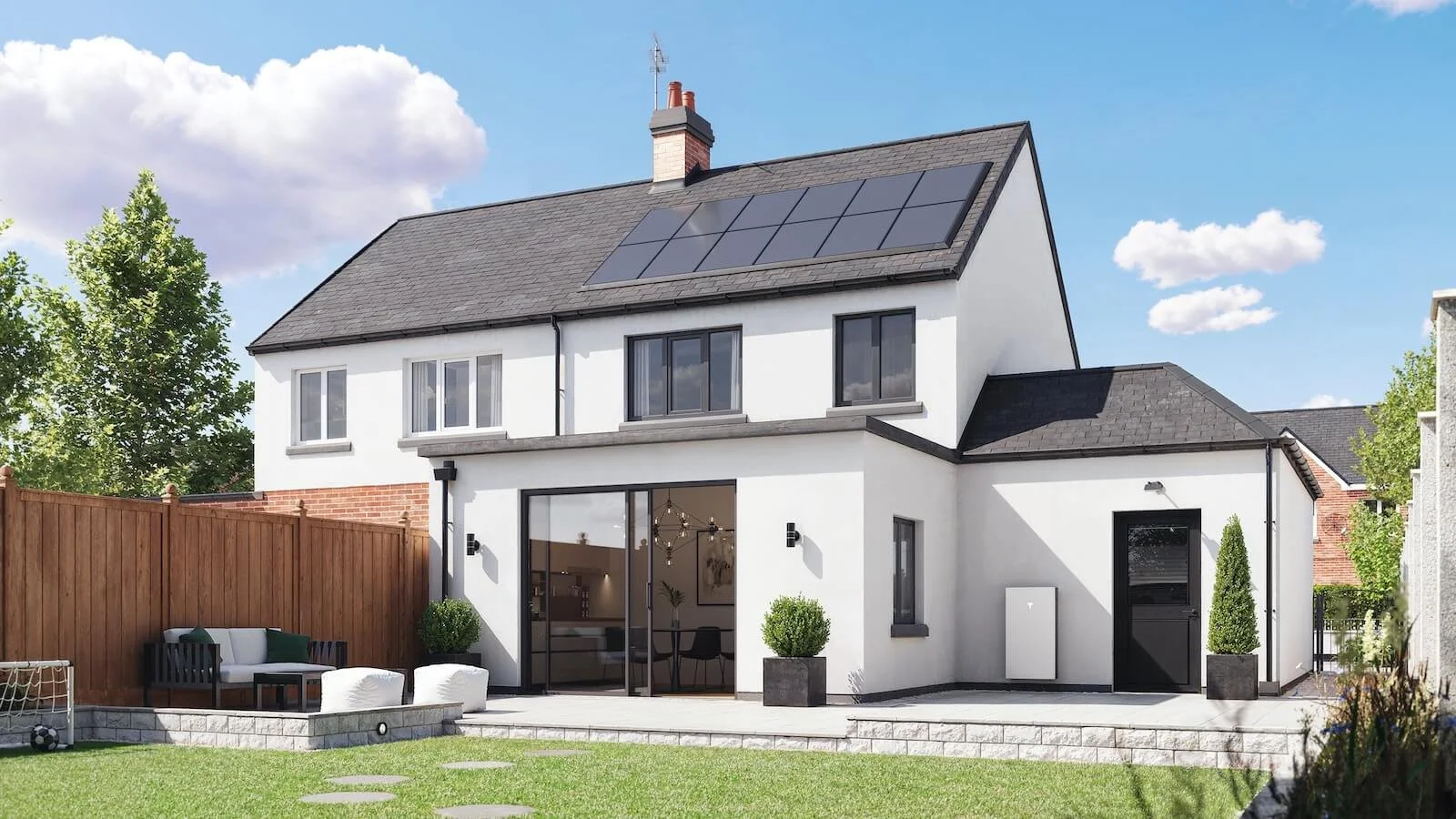 Tesla Powerwall home battery mounted on the rear wall of a modern house with rooftop solar panels