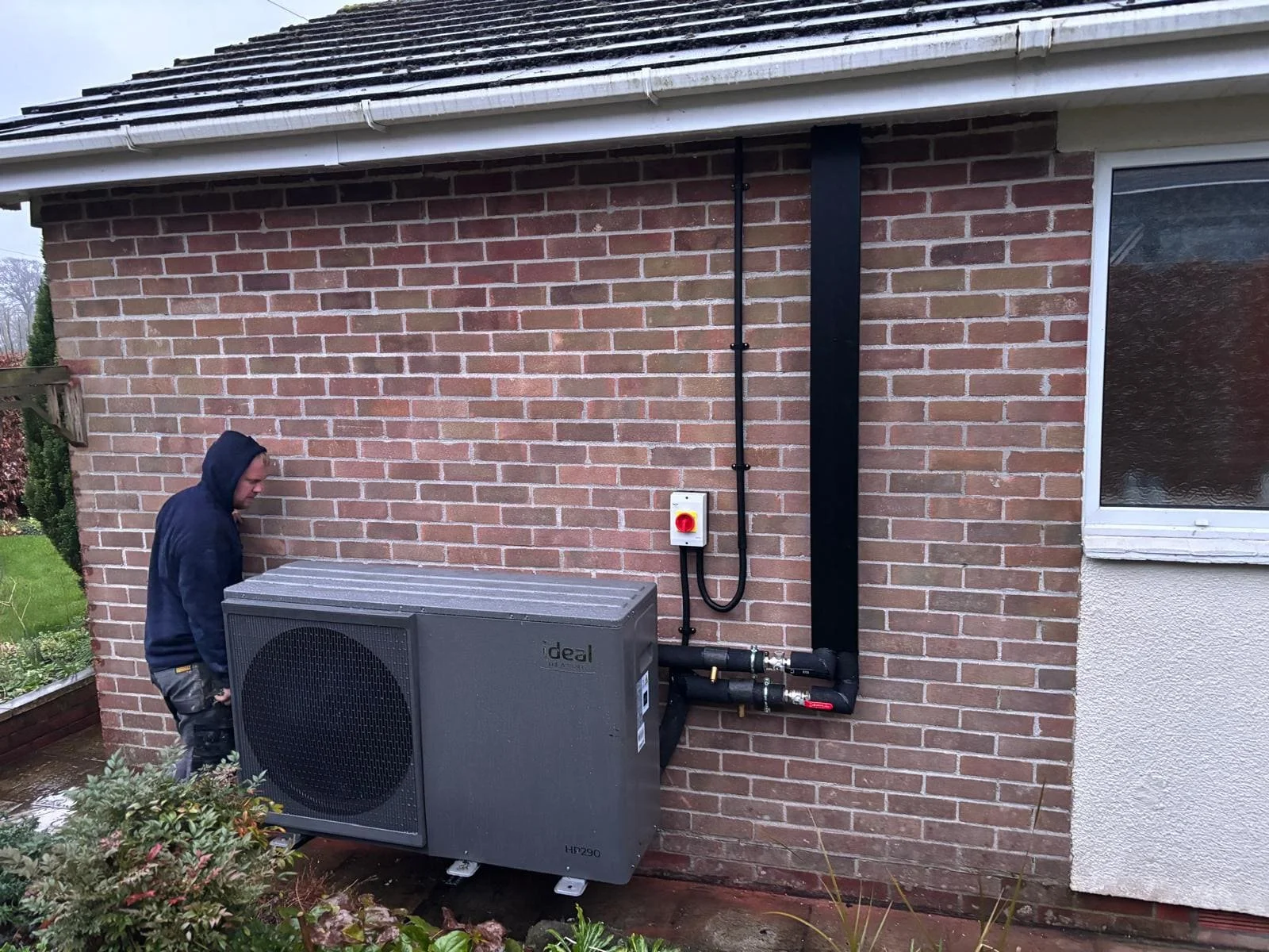 Heating engineer fitting pipework during an air source heat pump installation
