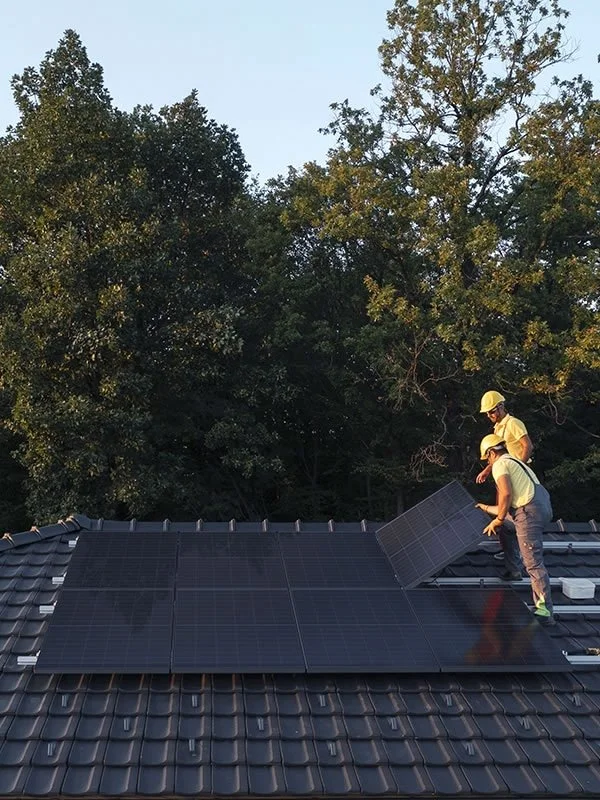 Installers fitting all-black Aiko Neostar solar panels on a pitched tiled roof