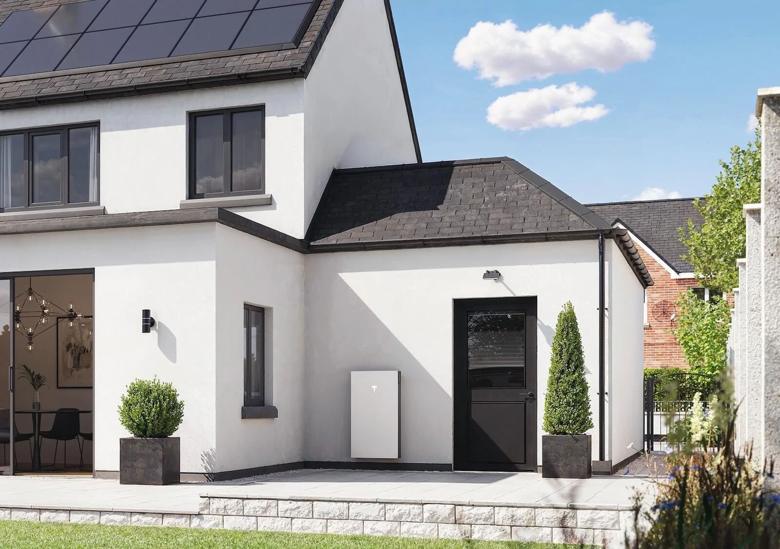 Tesla Powerwall battery storage installed on the exterior wall of a Saltash home, with rooftop solar panels visible above.