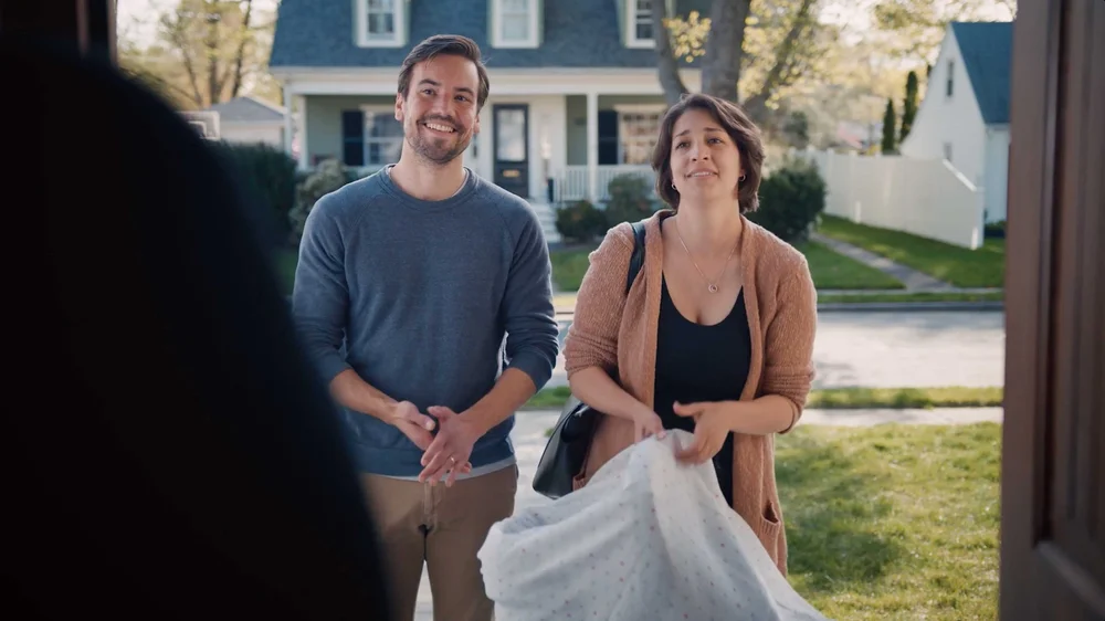 Couple smiling at front door with baby in comedic Uno Pizzeria & Grill commercial