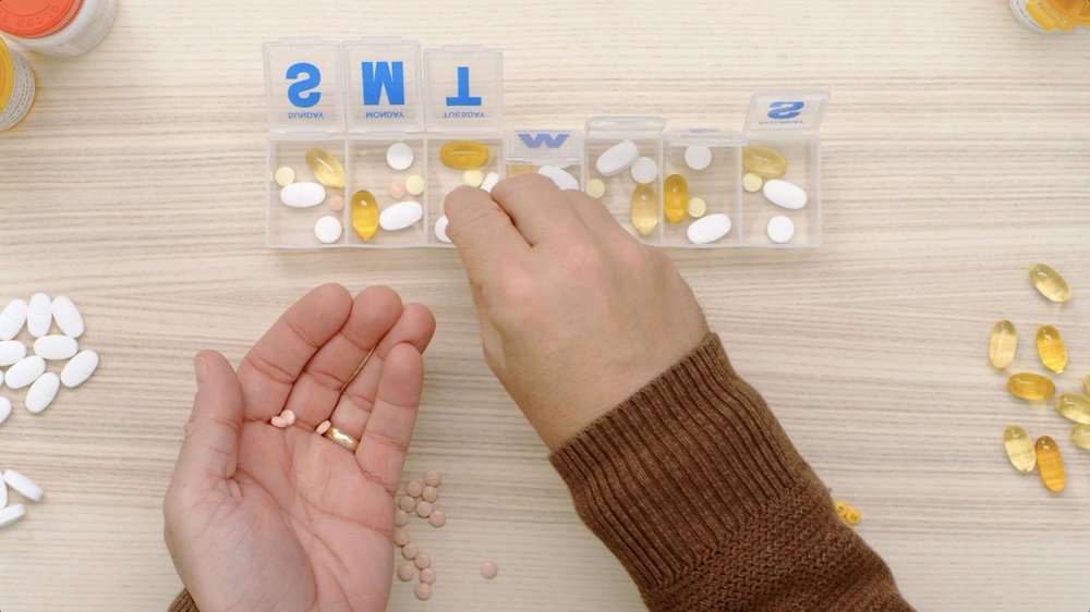 PillPack TV Ad man sorts piles of medication on wooden table