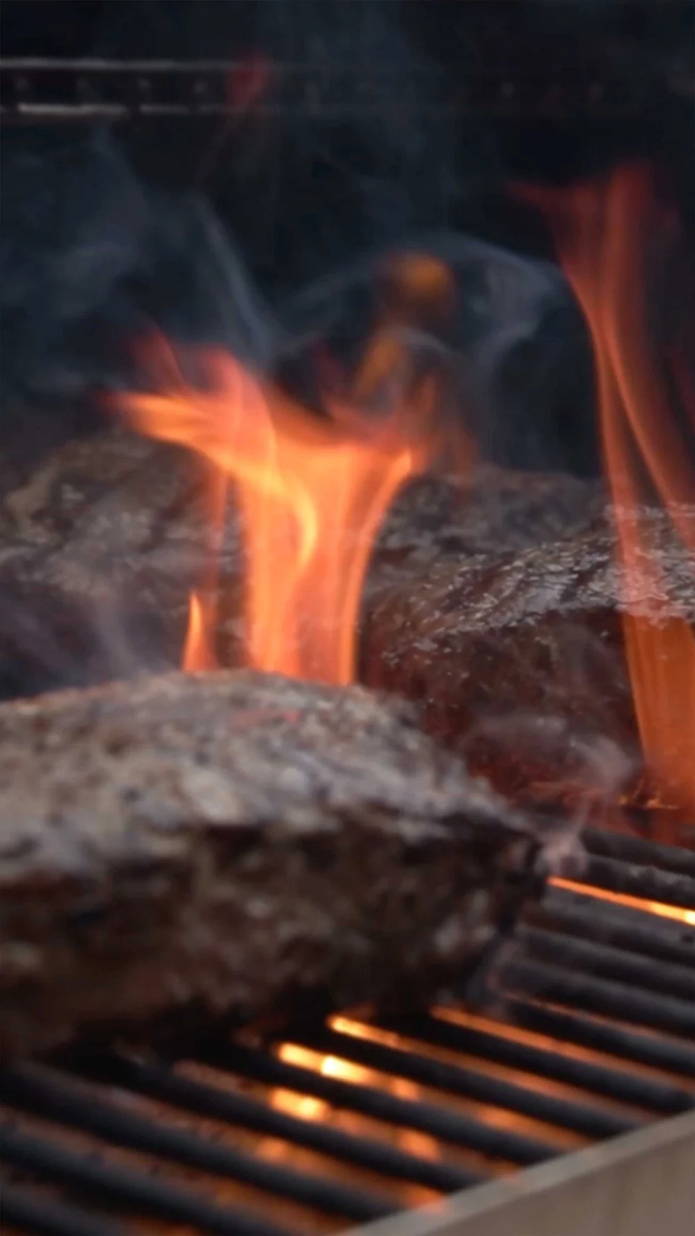 Close up of steak on a grill with fire in a vertical video for social for BBQ Guys
