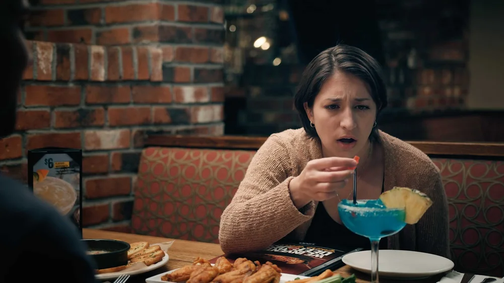 Woman looking at a blue cocktail and appetizers at Uno Pizzeria & Grill in commercial spot