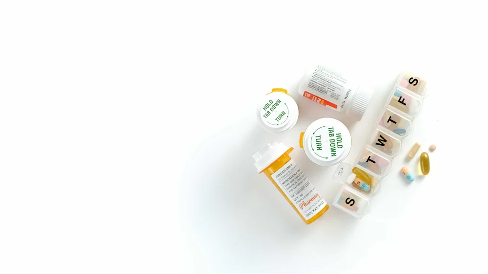 Pill bottles, pills, and sorter on a white table.