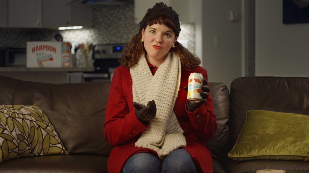 A woman sits on the couch holding up a Harpoon Rec League IPA in the Harpoon Brewery Social Media Ad