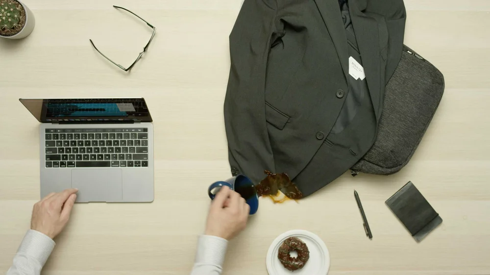 Ministry of Supply, Made for Travel Social Media Ad, topdown of desk man spills coffee on suit jacket