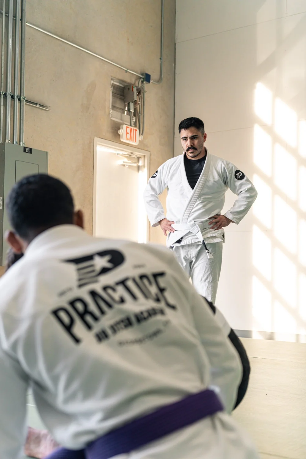 An instructor teaching a technique to students in Practice Jiu Jitsu gis during an adult class in Georgetown, TX