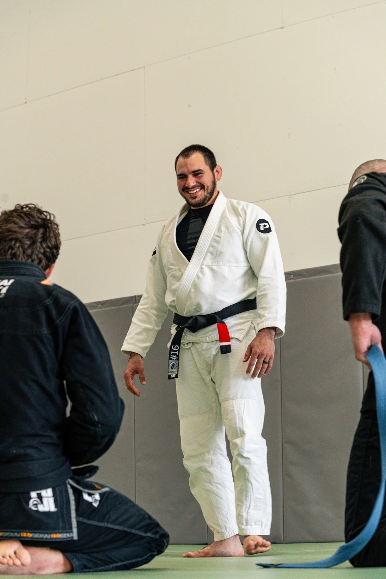 A black belt coach laughing with students during an adult jiu jitsu class at Practice Jiu Jitsu in Georgetown, TX