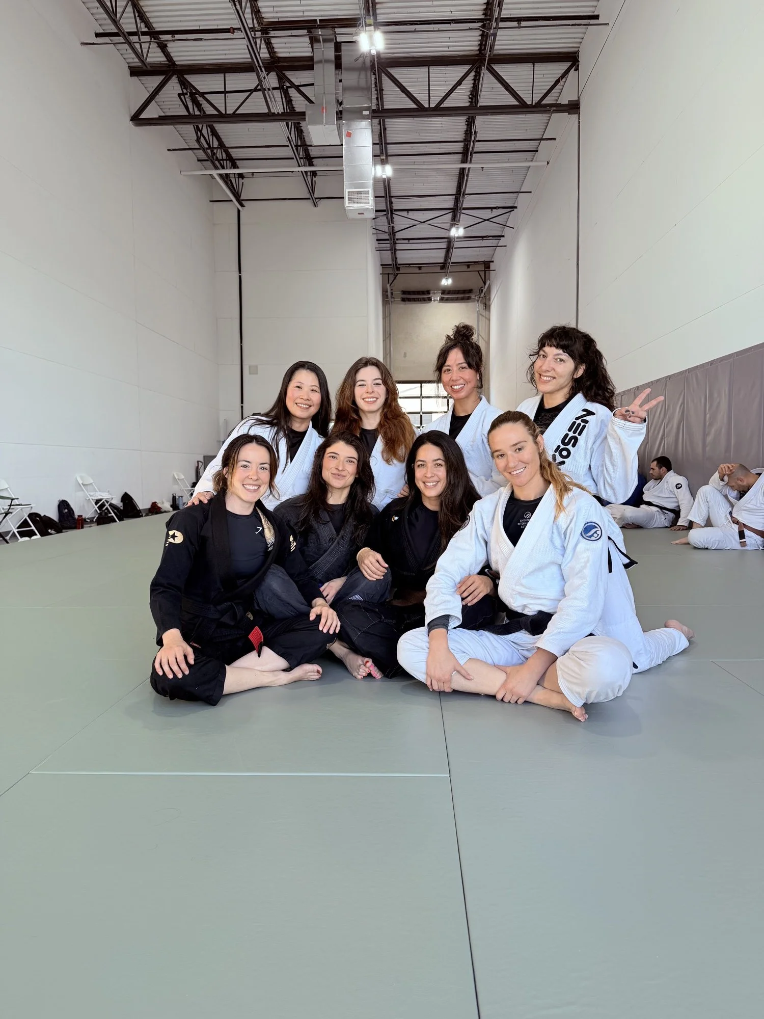 Eight women in gis sitting together on the mats after training at Practice Jiu Jitsu in Georgetown, TX