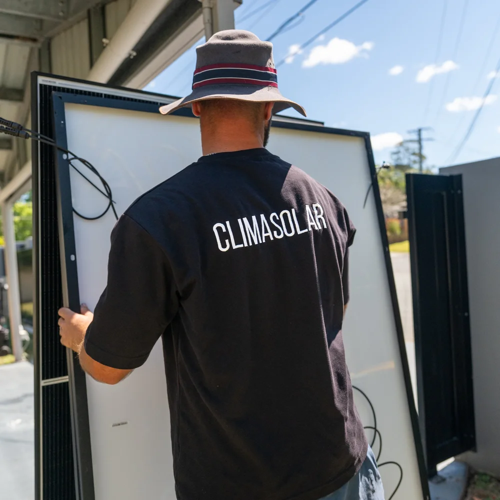 ClimaSolar installer carrying a solar panel on installation day